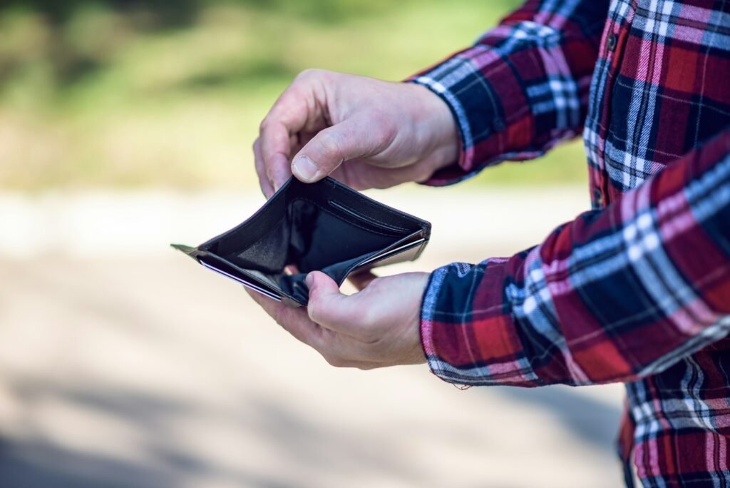 person in red blue and white plaid long sleeve shirt holding black leather bifold wallet