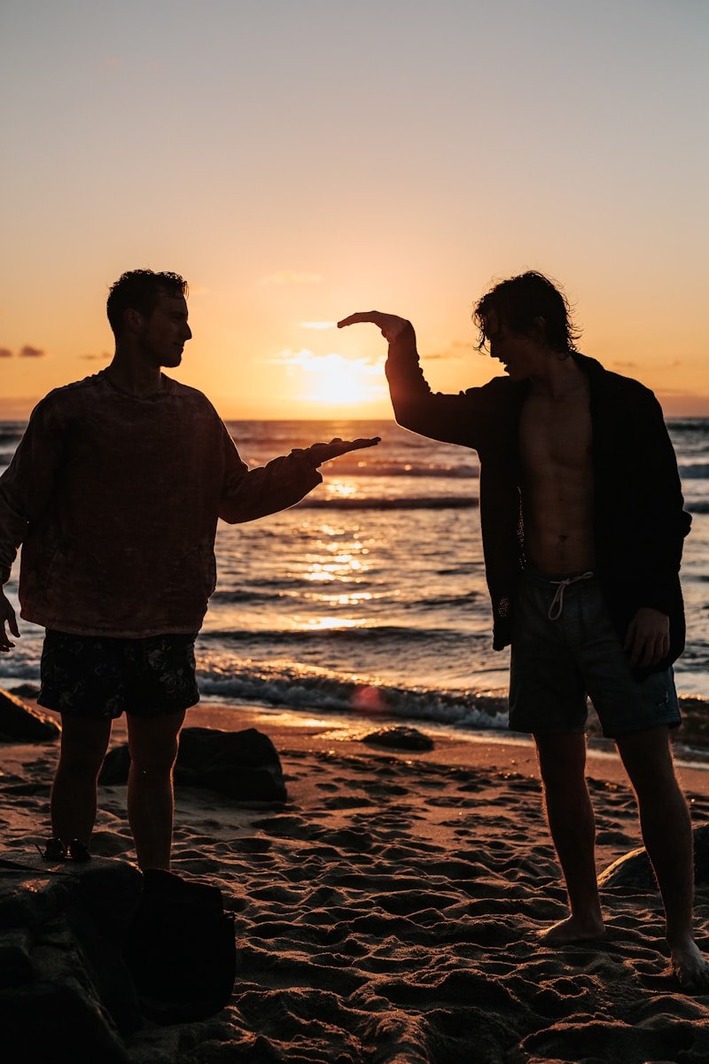 close-up photo of two men shaking hands near beach at sunset